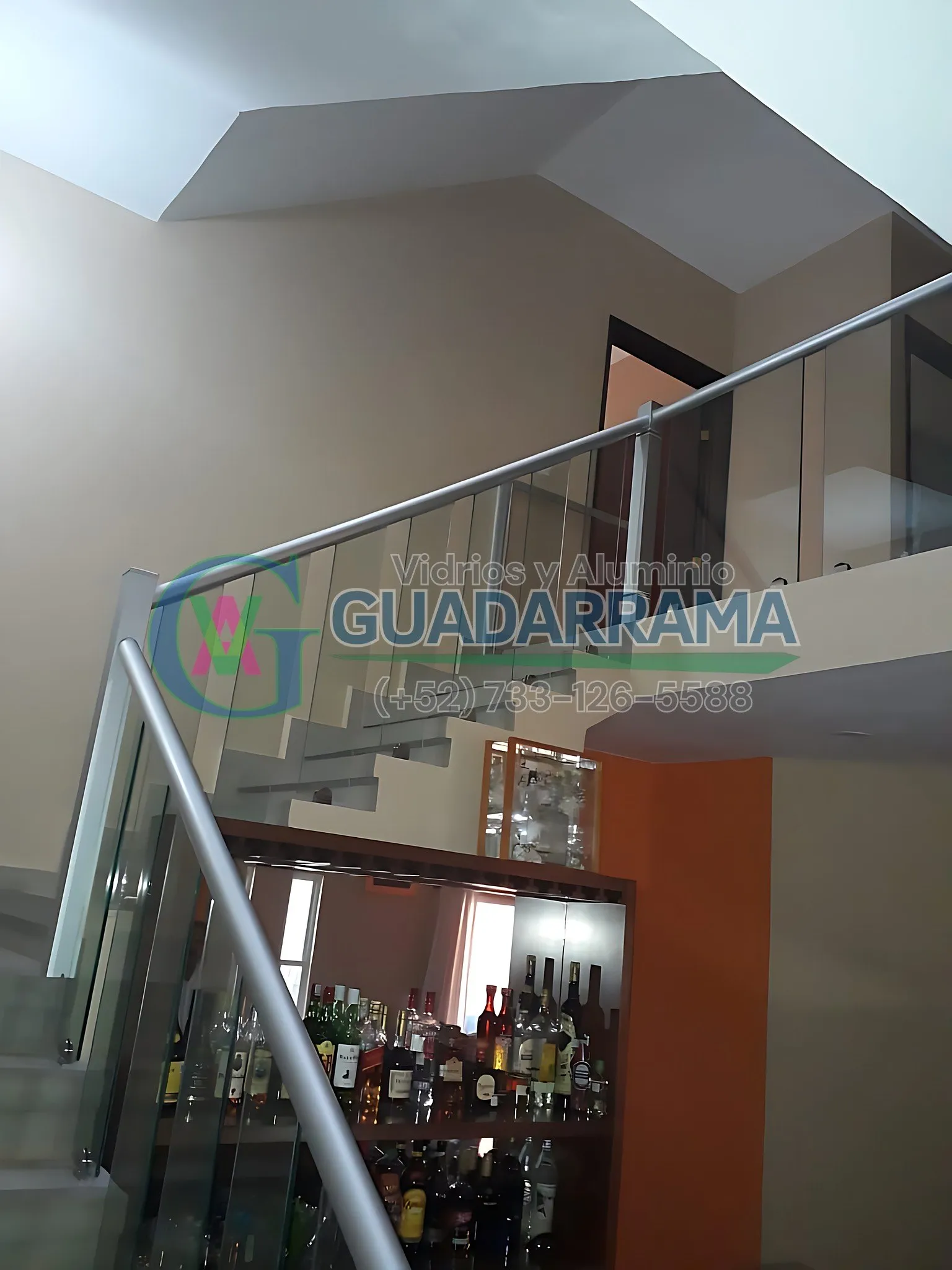 Barandal de vidrio templado transparente instalado en escalera con pasamanos de aluminio, limpio, seguro y con acabado que deja pasar la luz sin perder resistencia.