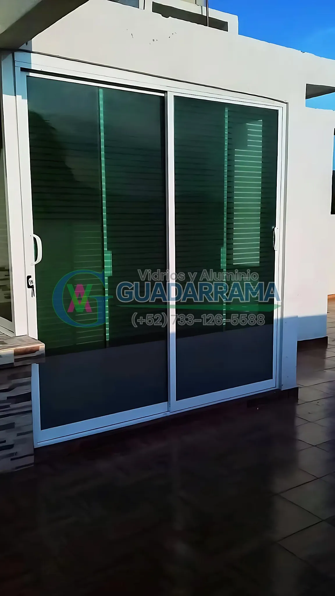 Cancel corrediza exterior en aluminio blanco, con vidrio Tintex y película esmerilada con líneas horizontales para privacidad y estilo.