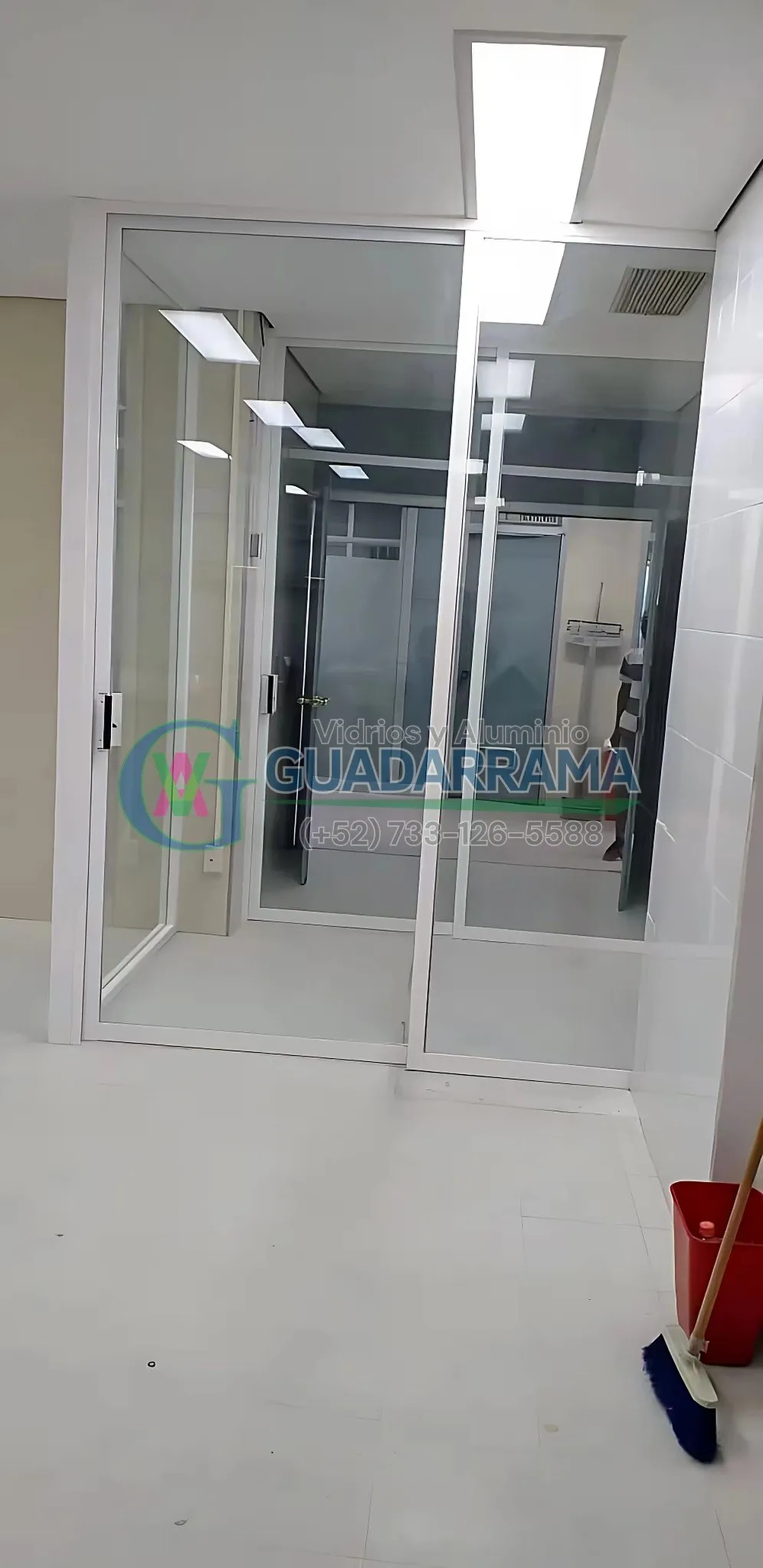 Cancel divisor corredizo en aluminio blanco con vidrio transparente y película de seguridad, ideal para oficinas, hospitales o escuelas.