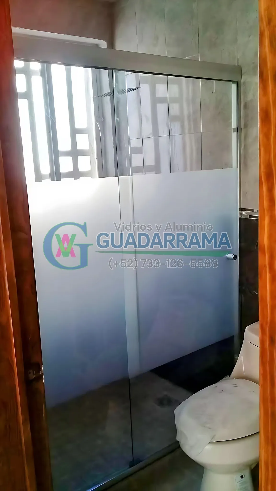 Cancel corredizo para baño en vidrio templado, con película esmerilada en la parte media para privacidad.