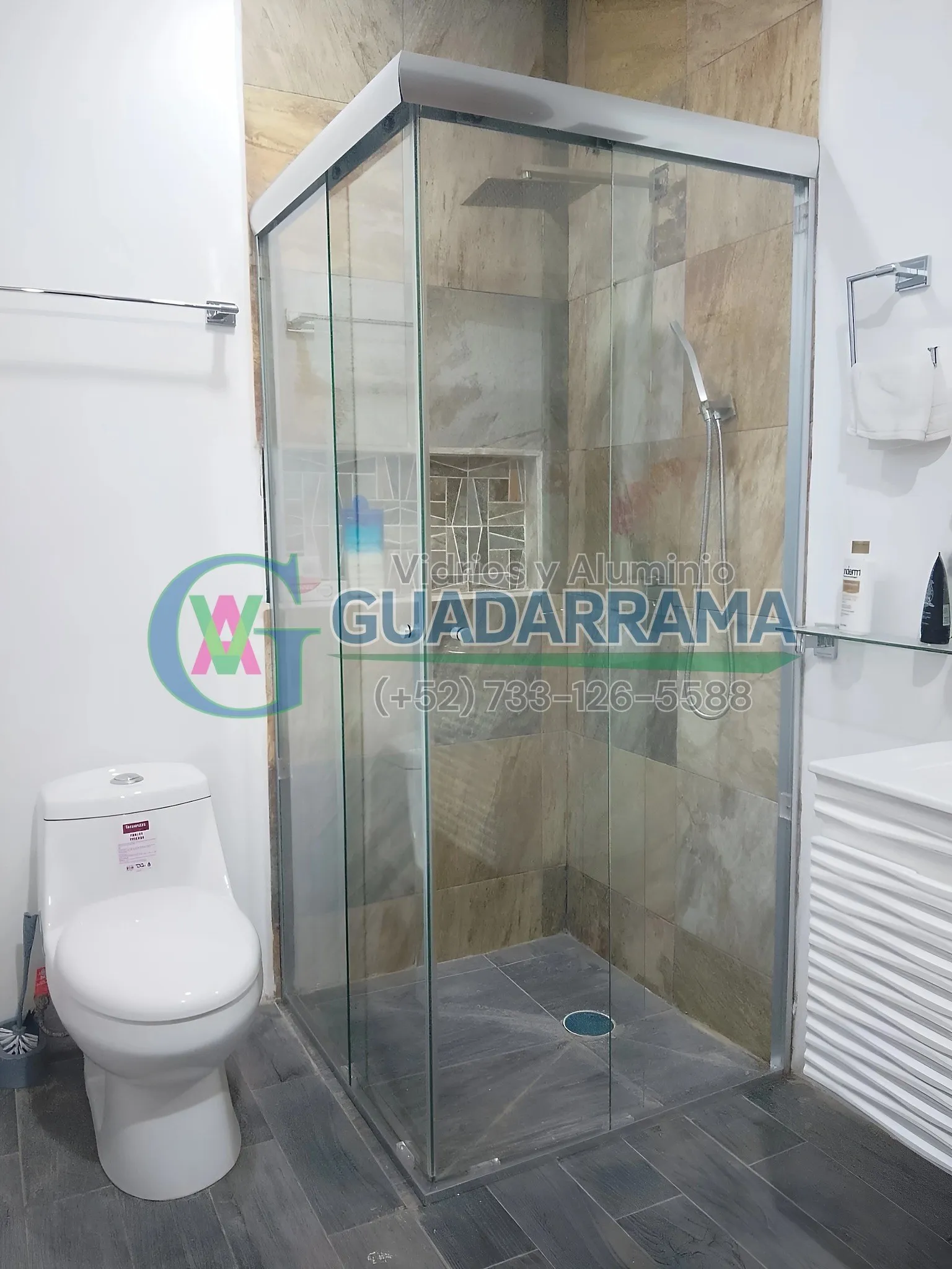 Cancel de baño en vidrio templado transparente, con puerta corrediza y fijo lateral, instalado en esquina.