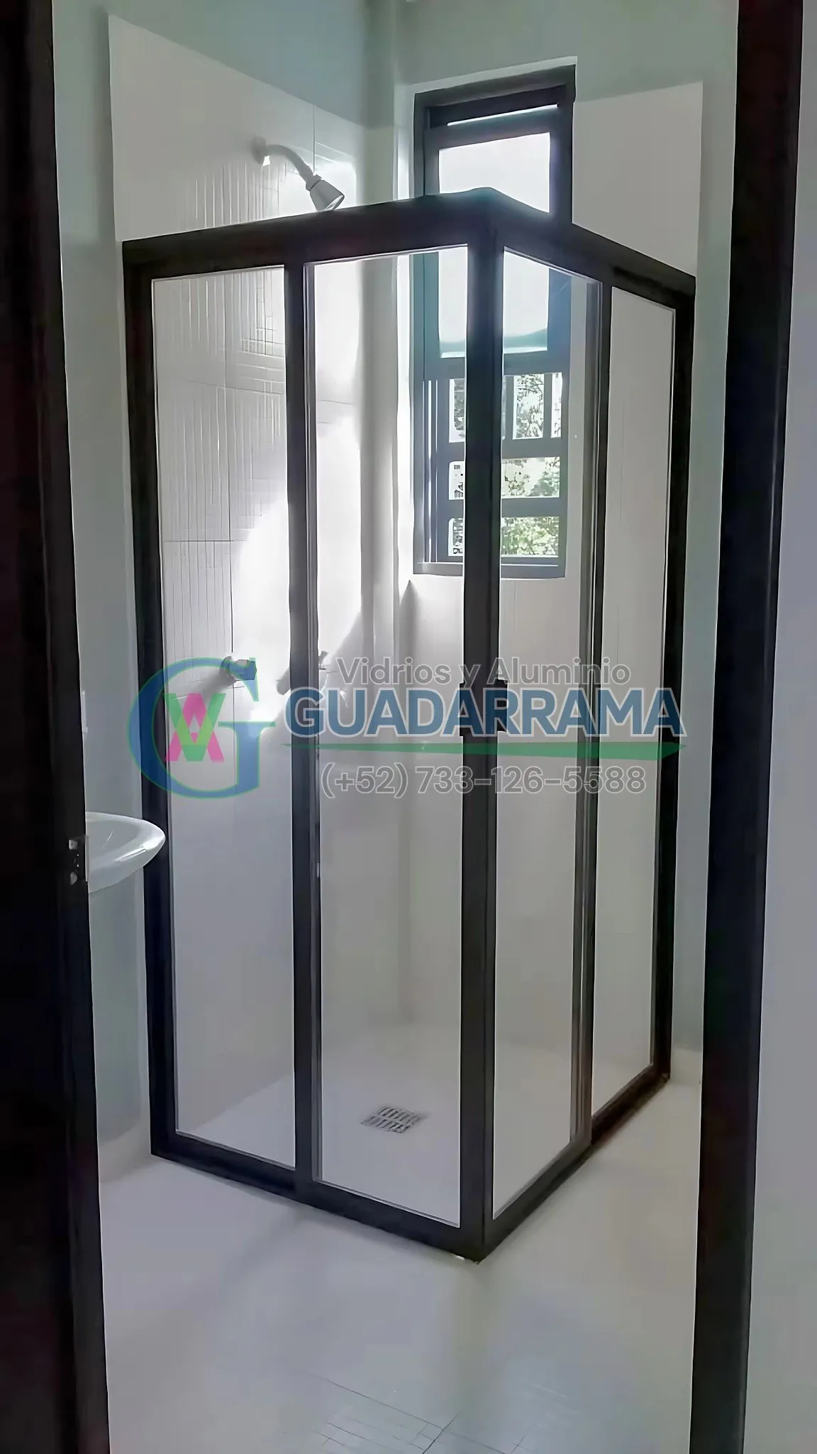 Cancel de baño en perfil negro con vidrio templado transparente, instalada en esquina con fijo y puerta corrediza.