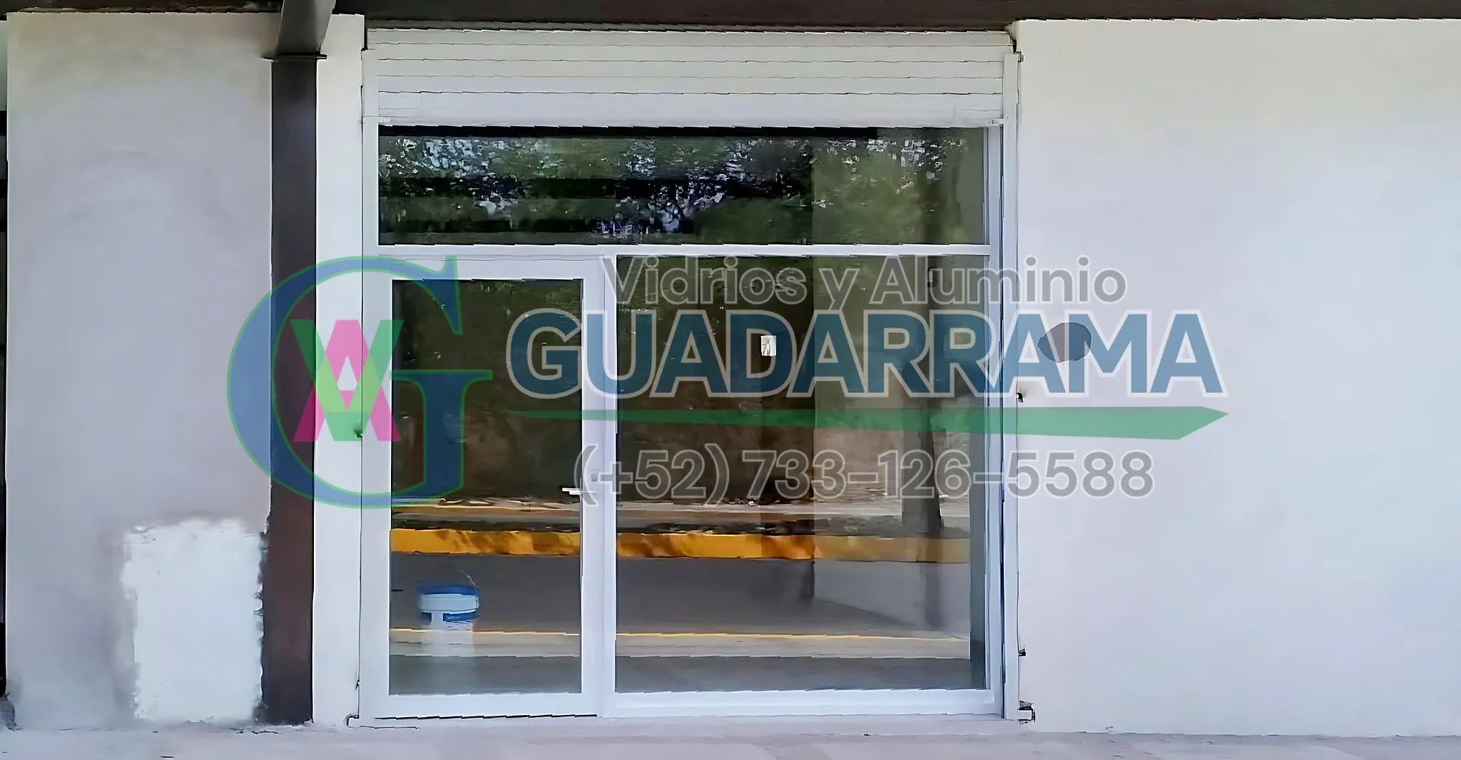 Cancel de aluminio blanco con puerta tipo bandera y antepecho de vidrio fijo, ideal para entrada de oficina o local comercial.