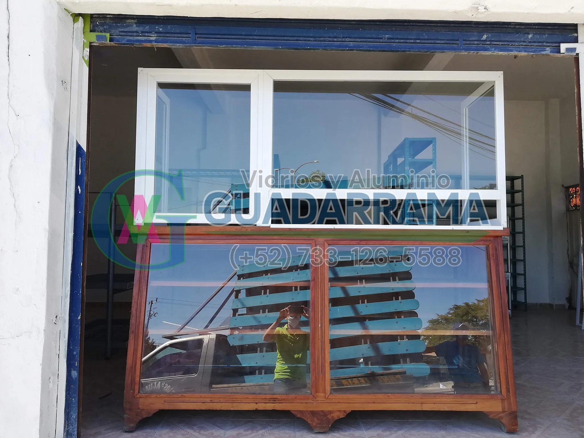 Vitrina para exhibidor, con perfilería blanca en la parte alta y marco de madera en la vitrina inferior.