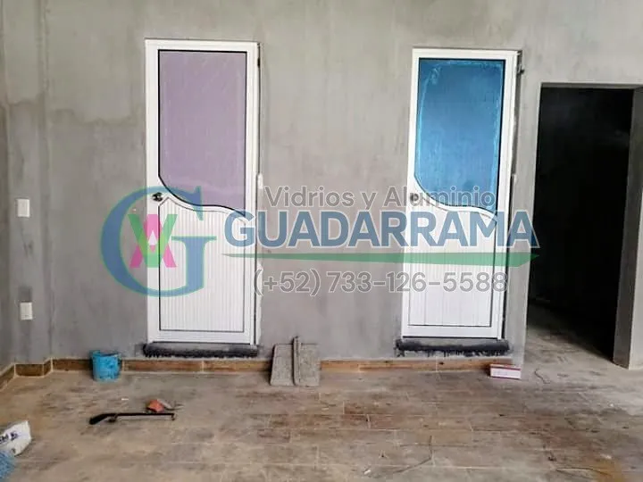Puertas abatibles para baño con plástico en colores rosa y azul, marco blanco y duela de aluminio.