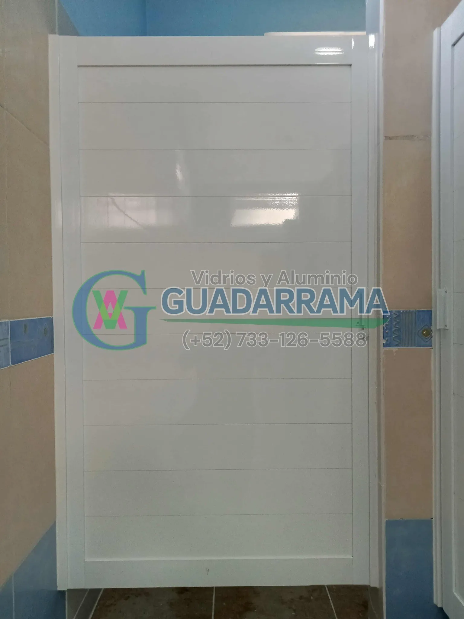 Puerta abatible para baño, en aluminio blanco con duela lisa.