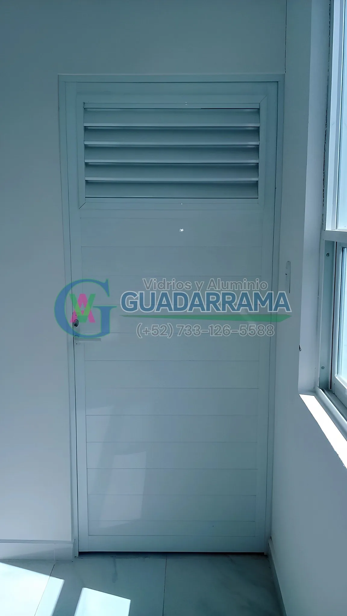 Una puerta abatible de aluminio blanco con duela liza, un acabado que combina funcionalidad y estética.