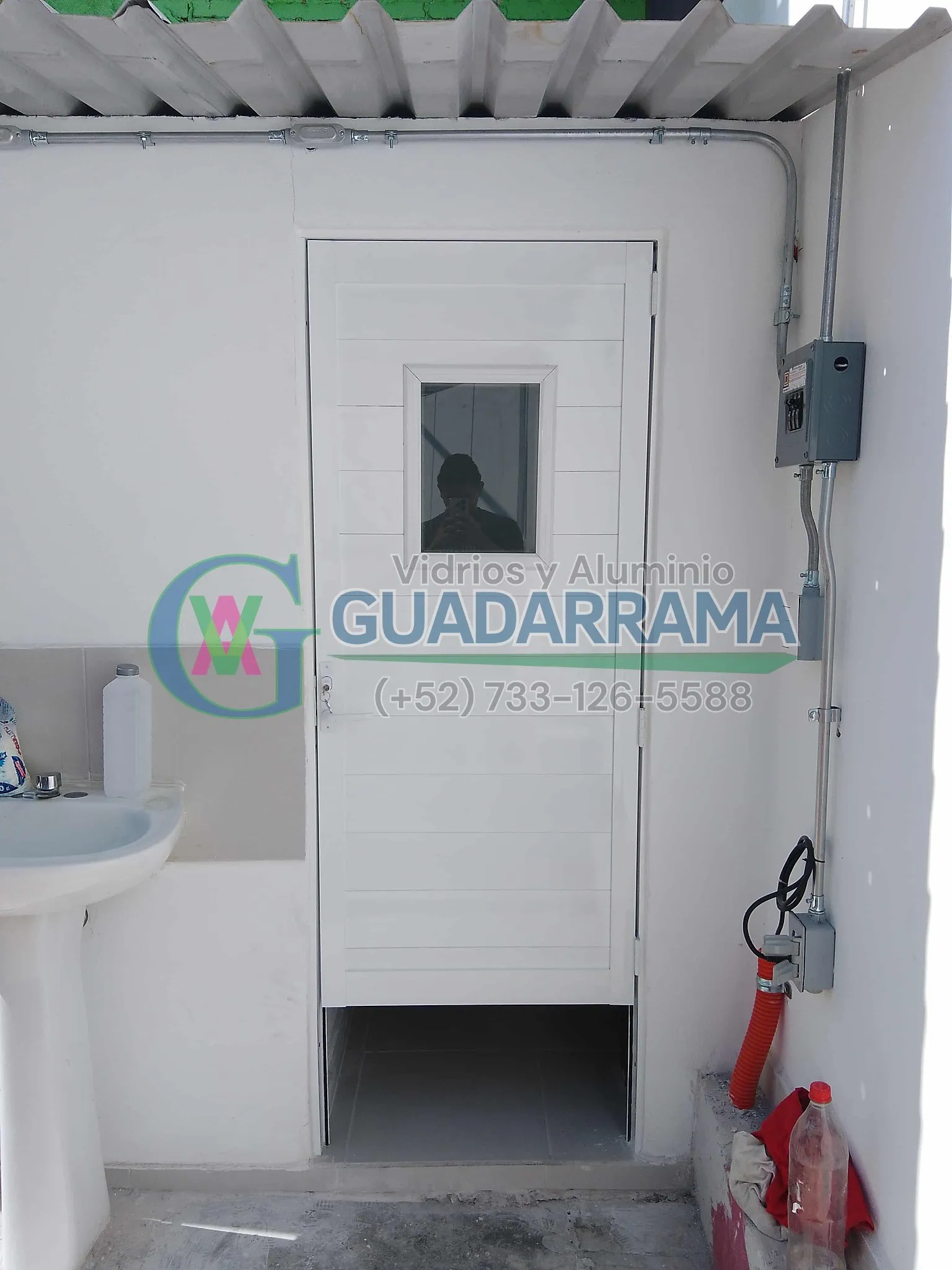 Puerta abatible de aluminio en blanco para baño, con panel de vidrio filtrasol y acabado esmerilado para una privacidad total.
