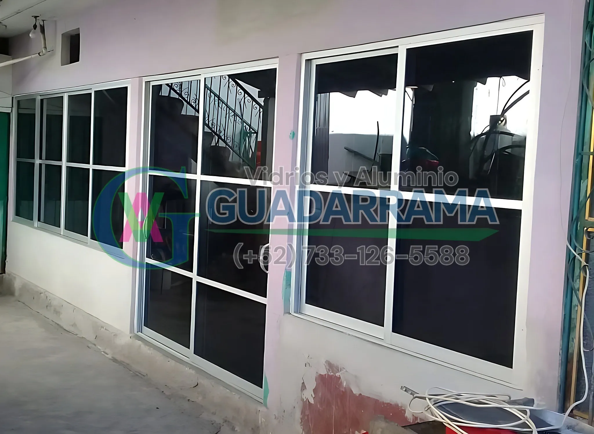Puerta abatible para exterior en aluminio blanco, con panel de vidrio filtrasol esmerilado que filtra la luz solar directa.