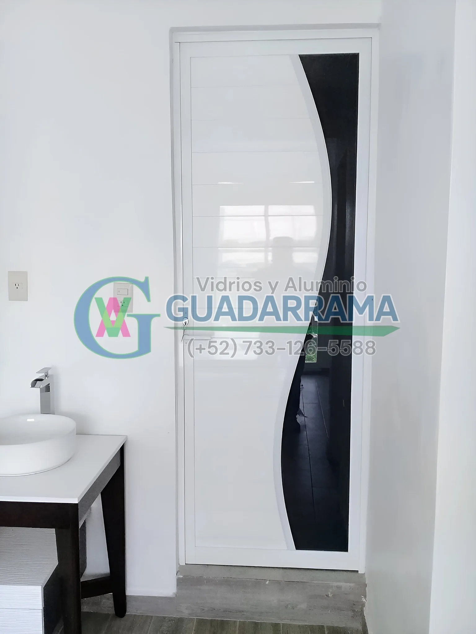 Puerta abatible en aluminio blanco con panel de vidrio filtrasol esmerilado.