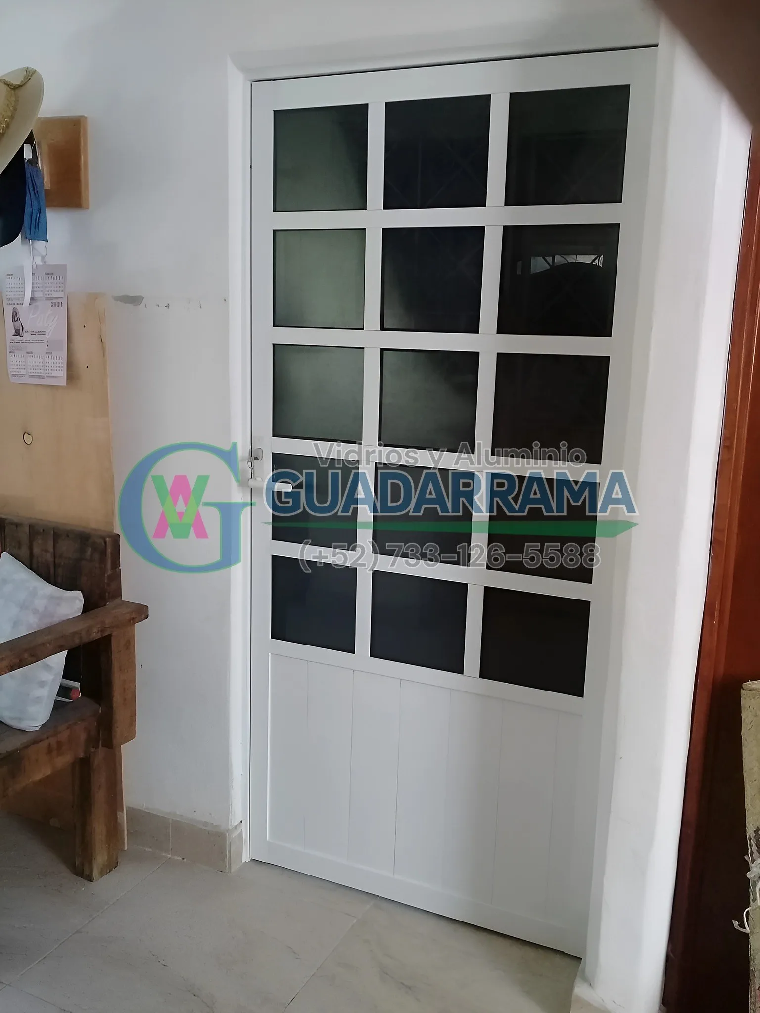 Una puerta abatible en aluminio blanco con vidrio filtrasol, ideal para divisiones interiores que filtran la luz solar directa.