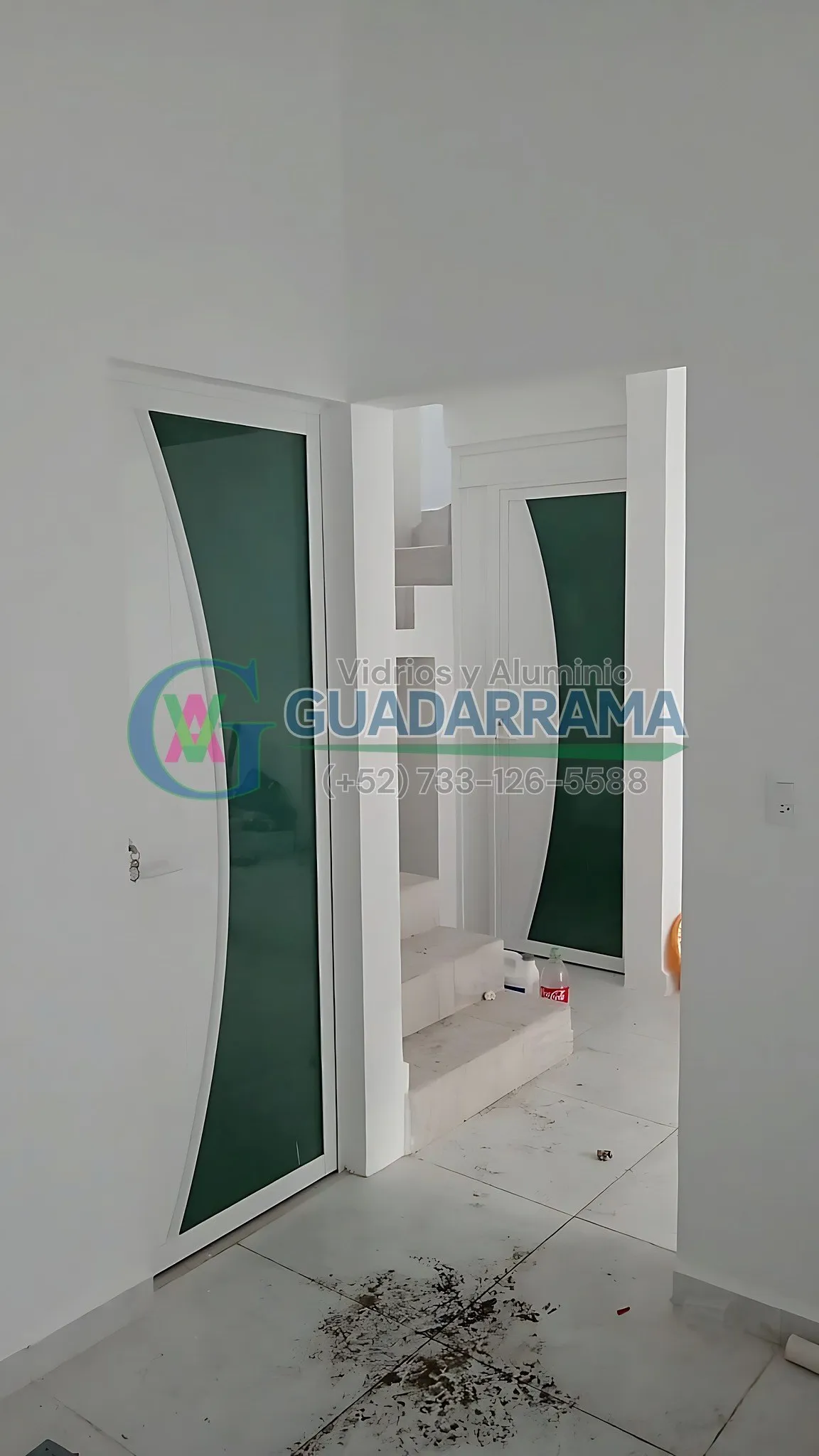 Puerta abatible en aluminio blanco con vidrio tintex curvo.