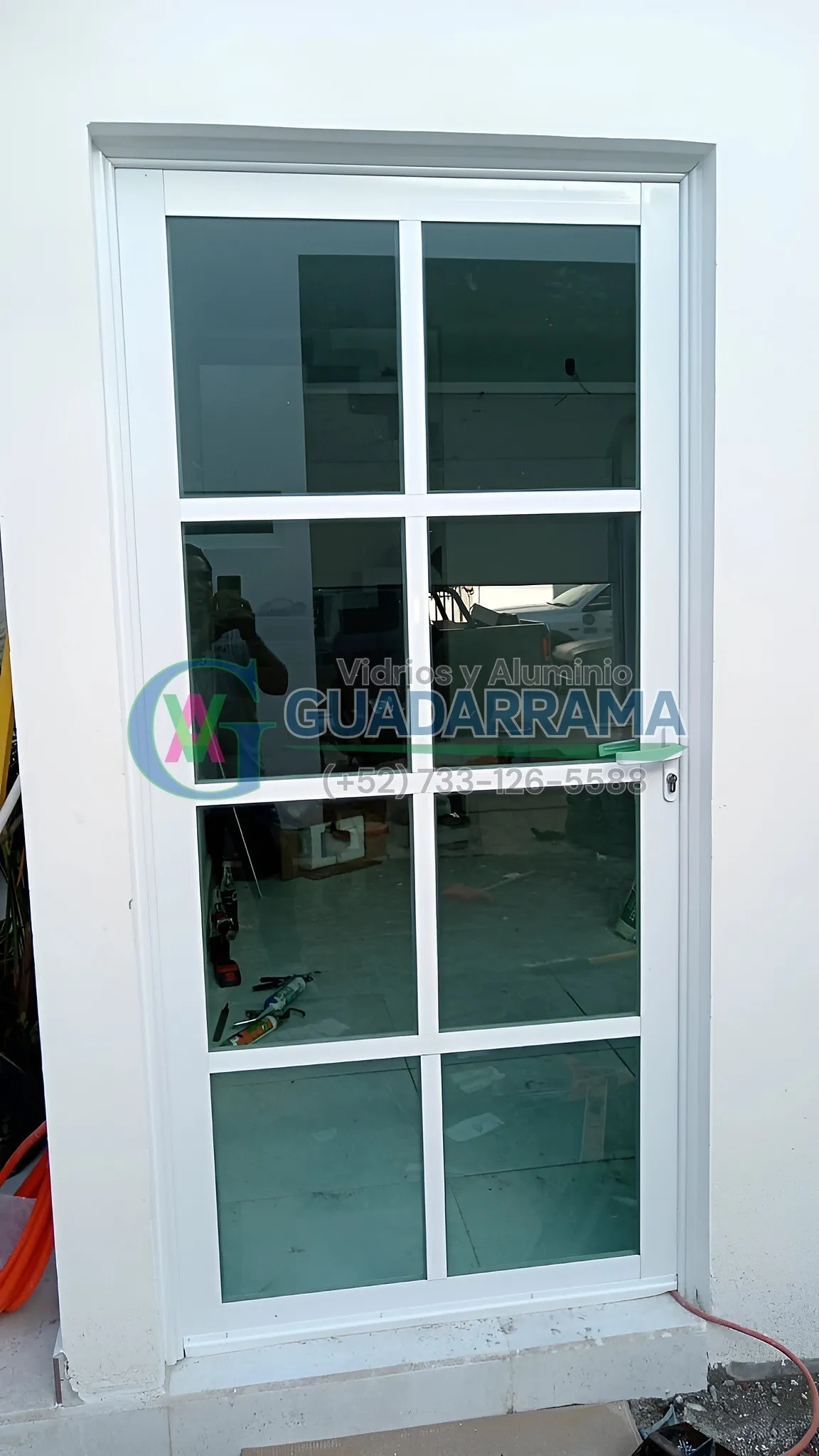 Puerta abatible en aluminio blanco con vidrio tintex.