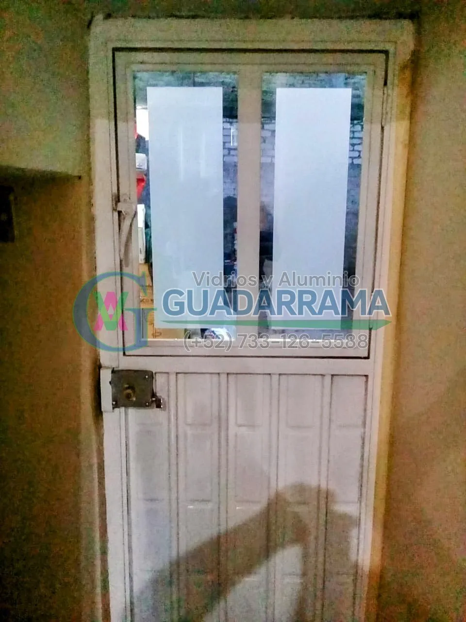 Puerta abatible de aluminio blanco para exterior, con vidrio transparente esmerilado y una película decorativa que le da un toque único.
