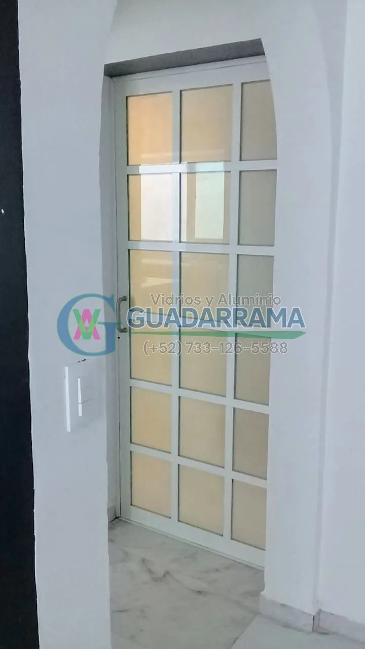 Una puerta abatible de aluminio blanco con vidrio transparente, perfecta para divisiones de espacios interiores.