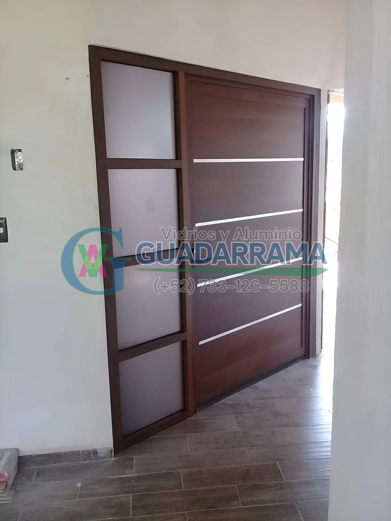 Una puerta de oficina abatible en madera, con panel de vidrio transparente esmerilado.