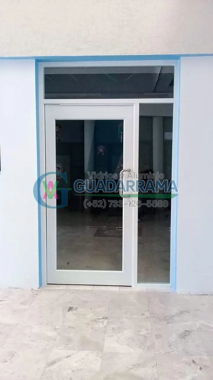 Puerta abatible de aluminio natural con vidrio transparente y cerco gran vista, ideal para espacios que buscan amplitud visual.