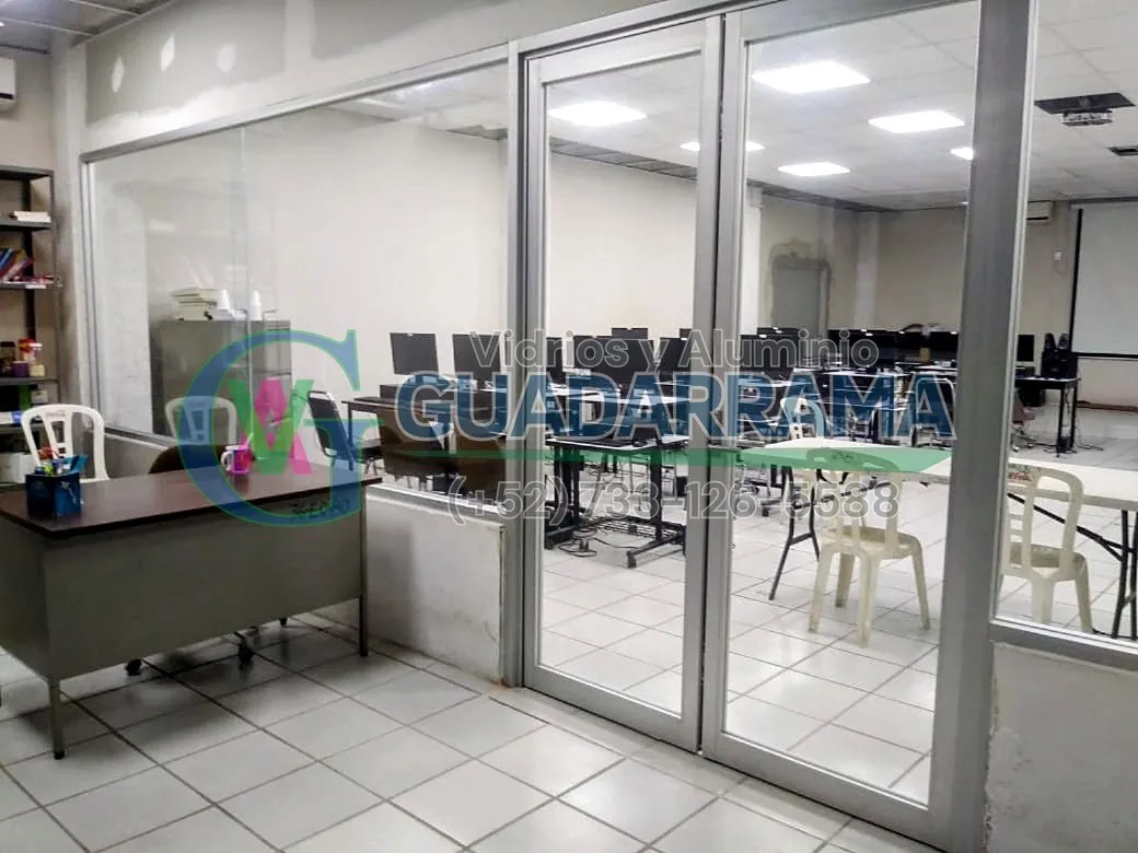 Para esta oficina, fabricamos e instalamos una puerta abatible de aluminio natural con vidrio transparente que permite mantener la fluidez visual y la entrada de luz.