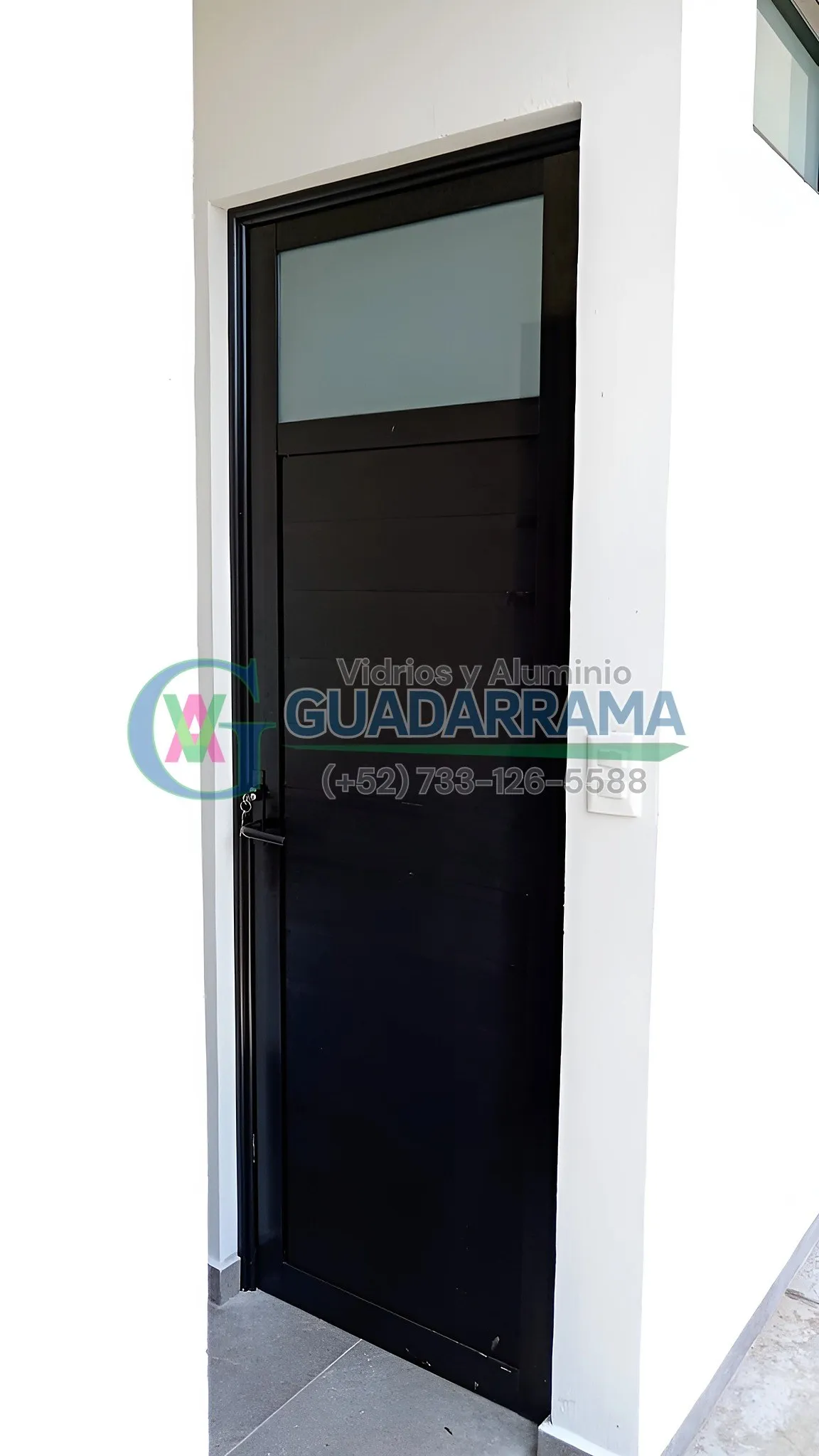 Puerta abatible de aluminio negro con vidrio transparente.