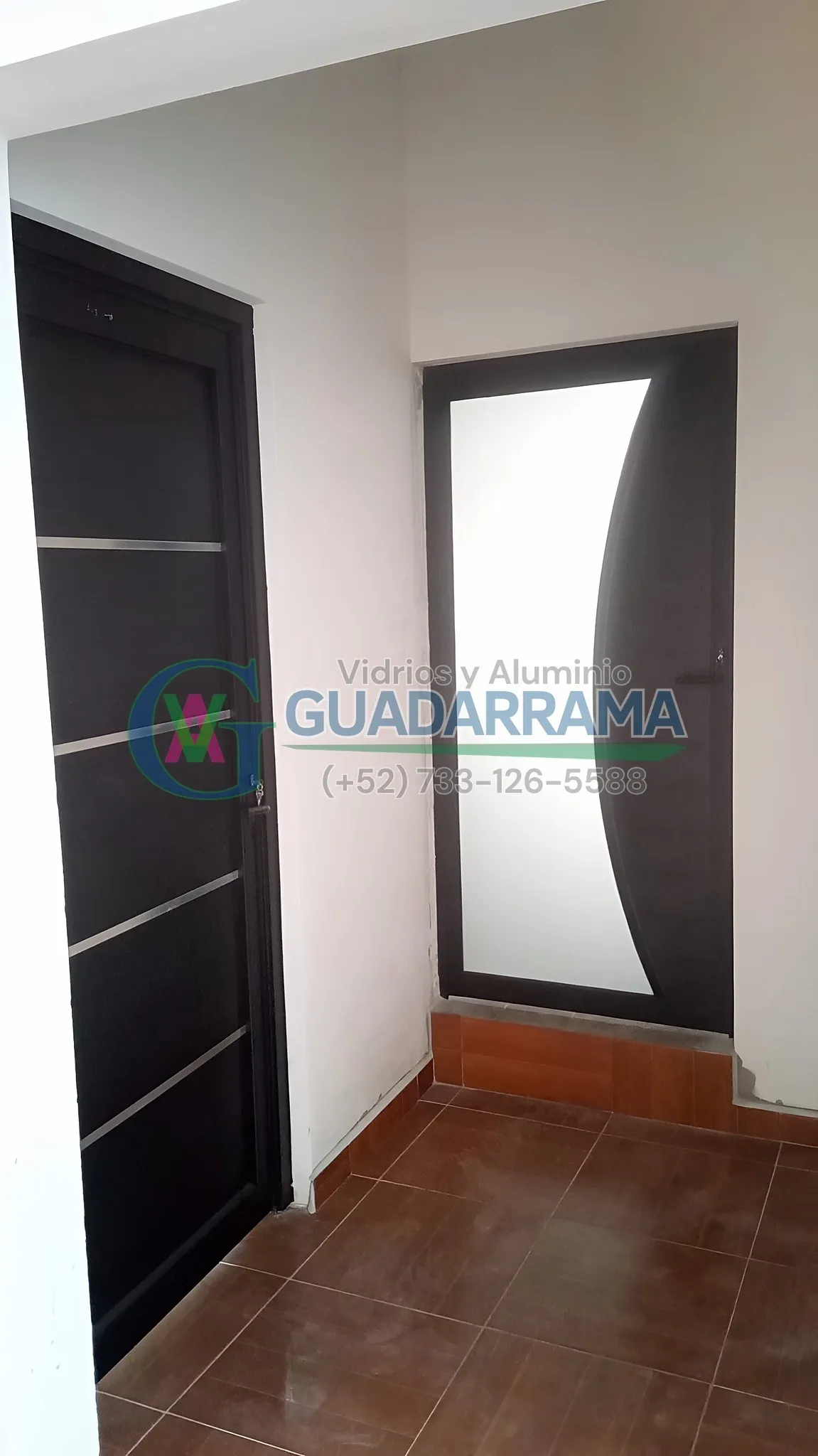 Puerta abatible con vidrio transparente esmerilado, con un perfil de aluminio negro.
