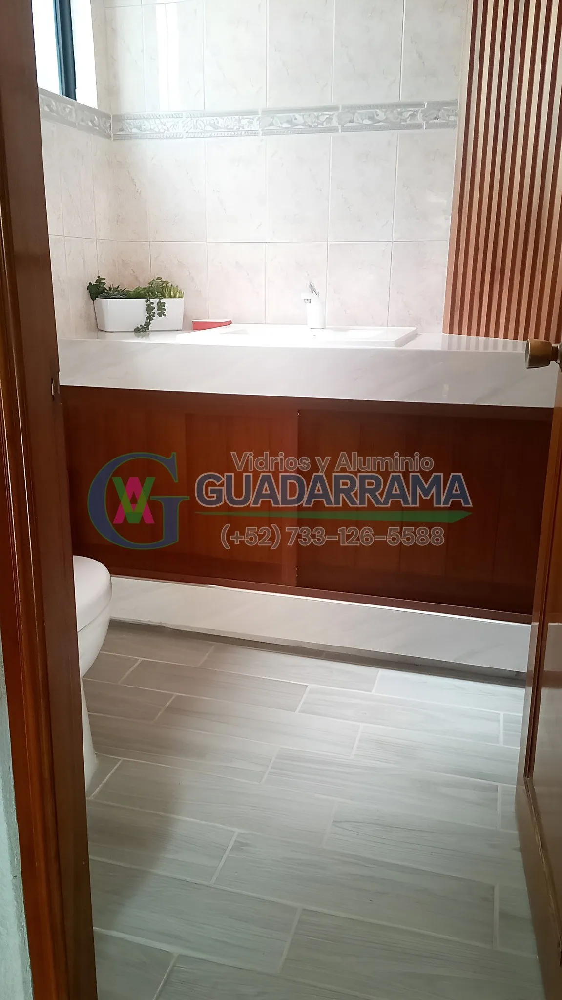 Puertas corredizas de aluminio acabado madera para baño, hechas con duela lisa para un acabado elegante y funcional.