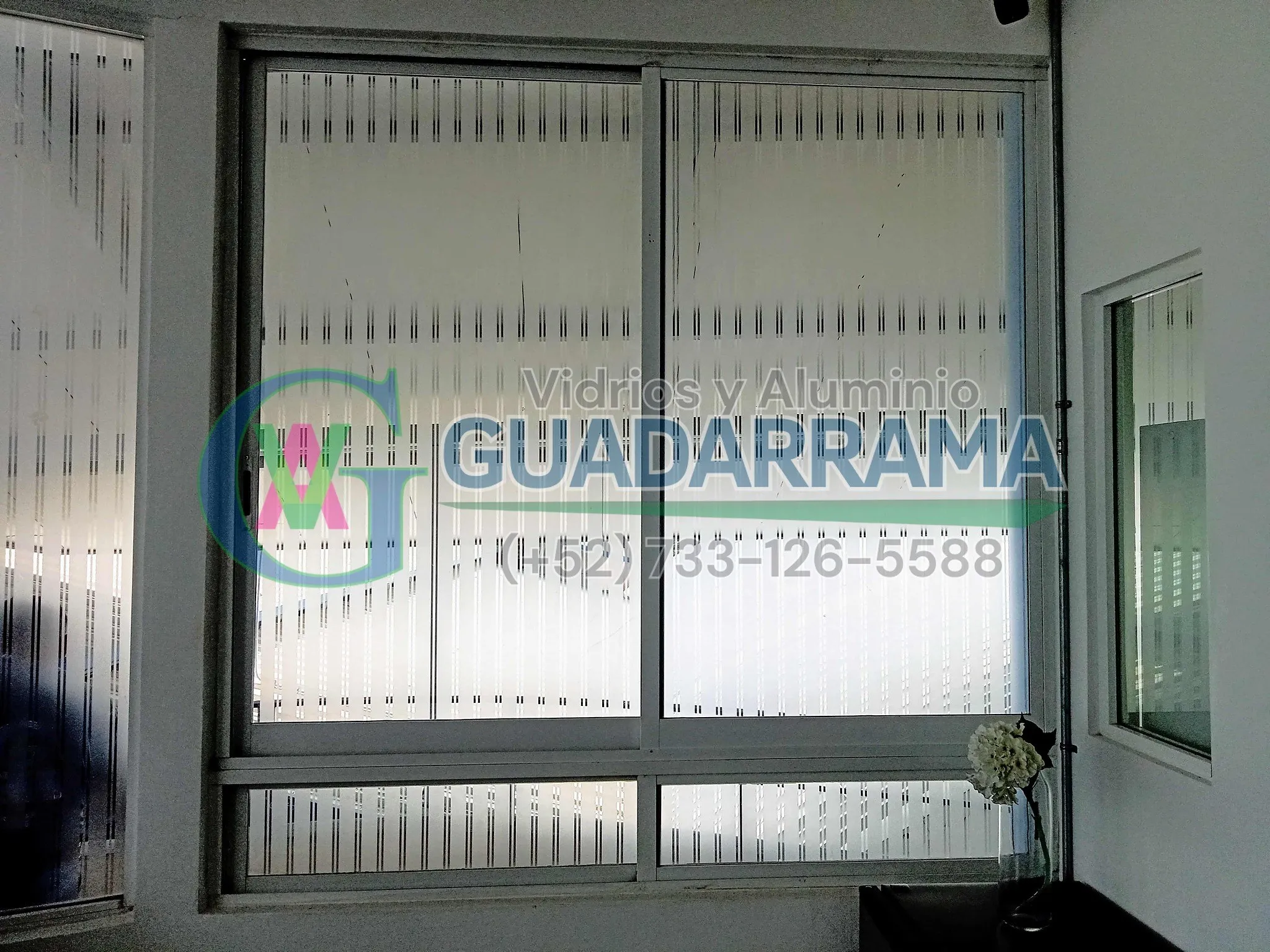 Una ventana corrediza para oficina con vidrio esmerilado, perfecta para separar espacios manteniendo la luz y la privacidad.