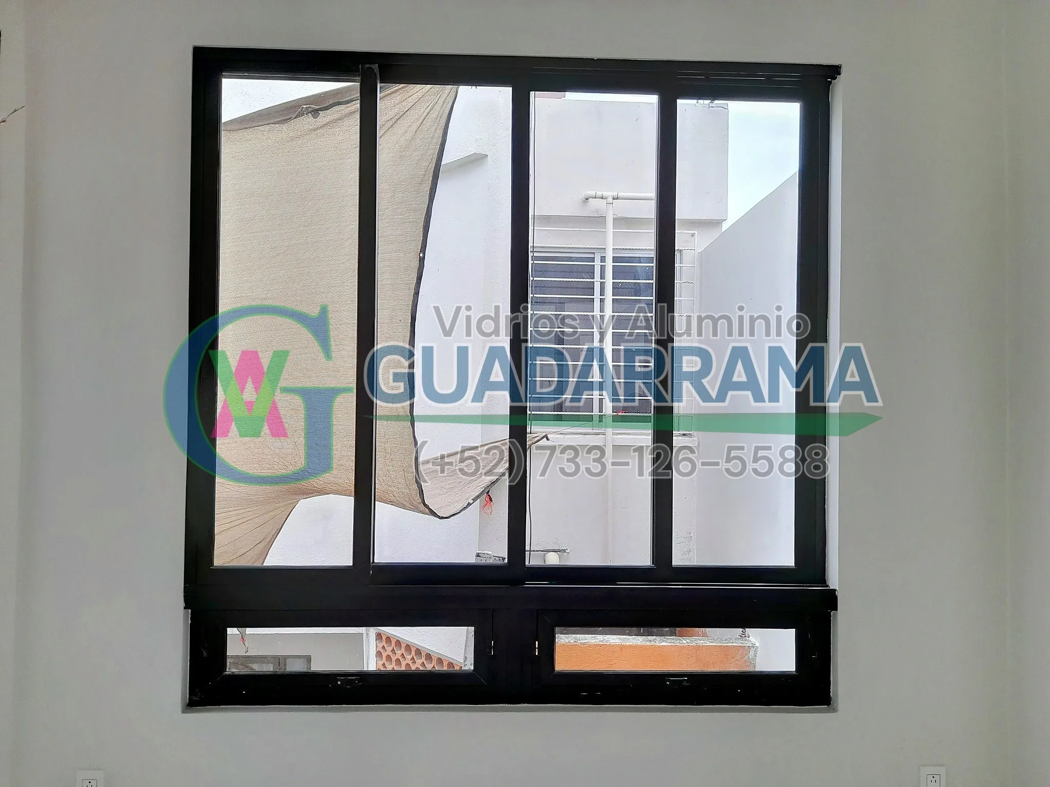 Una ventana fija de cancelería en aluminio negro con vidrio transparente, ideal para exteriores.